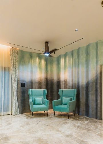 Living room with teal armchairs and wallpaper feature wall
